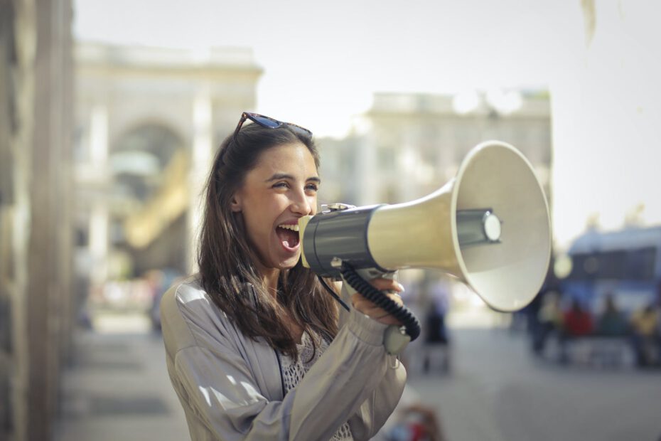 cheerful young woman screaming into megaphone